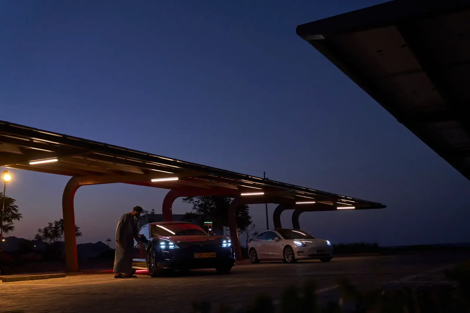 A solar shaded car port with an electric vehicle charging at dusk in the Yiti community